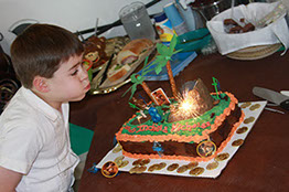 A boy blowing out candles on a birthday cake.