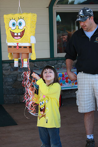 photo of a young girl holding a sponge bob pinata with a gentlemen standing next to her.
