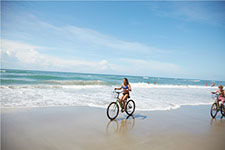 photo of people riding a bike on the beach.