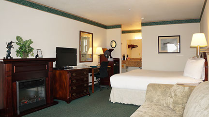 This spacious room is showing a European King Bed, Electric Fireplace, Chest of Drawers, Flat Screen TV, Writing Desk, Microwave and Mini Fridg.