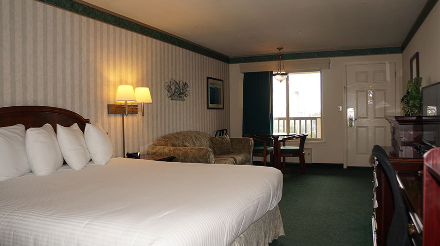 Photo showing European King Bed, sofa, table and chairs, large window, and fine furnishings.