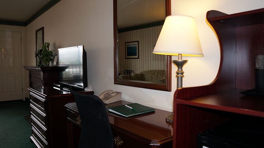 Photo showing writing desk with lamp, direct dial phone, large mirror, TV and fine furnishings.