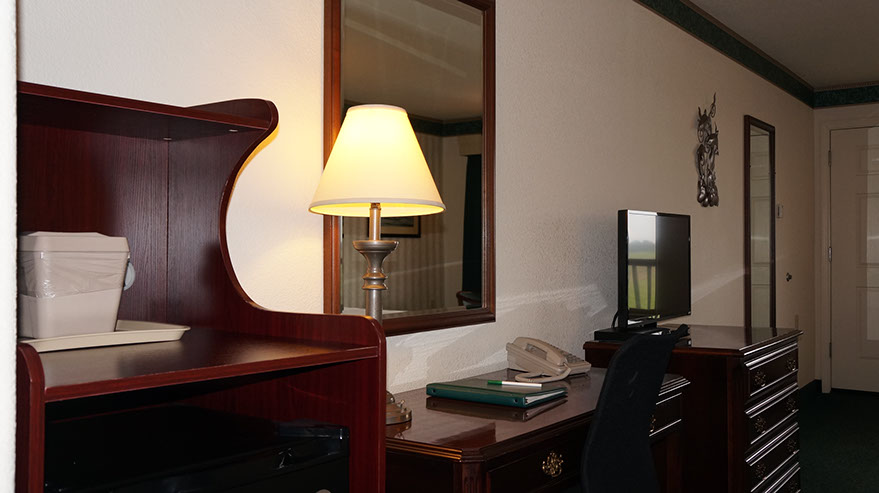 Photo showing fine furnishings with Microwave, ice bucket, writing desk, lamp, mirrors and dresser.