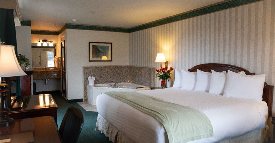 European King Size Bed guest room. Photo showing King Bed, Jacuzzi Tub, Writing Desk with lamp and phone.