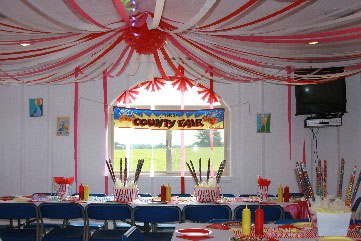photo of the party room with sign that reads "County Fair" Colors are mainly red and blue.