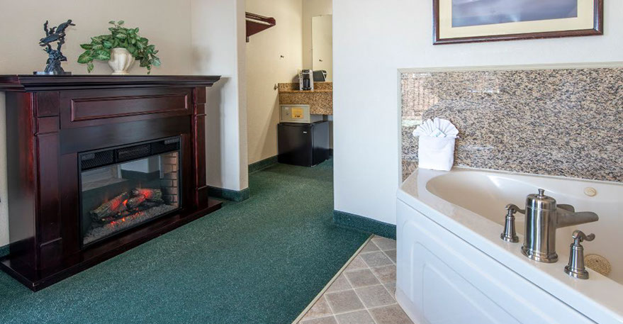 European King Size Bed guest room. Photo showing King Bed, Jacuzzi Tub, Writing Desk with lamp and phone.