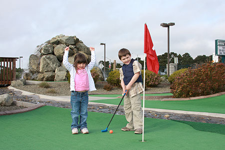 2 children having fun at a round of golf while at Ed's Mini Golf and Arcade.