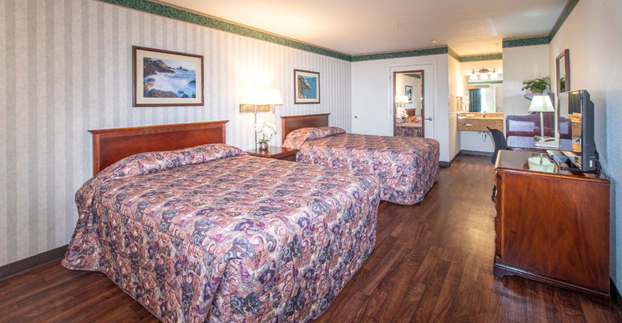 Photo showing 2 queen beds with night stand, double lamps and an alarm clock.