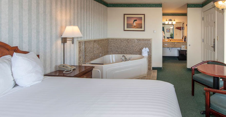 This pho shows our Queen size bed, Jacuzzi tub seats two. A Chest of drawers, night stand, lamp, alarm clock, direct dial phone and decorations 