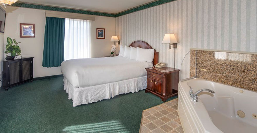 This pho shows our Queen size bed, Jacuzzi tub seats two. A Chest of drawers, night stand, lamp, alarm clock, direct dial phone and decorations 