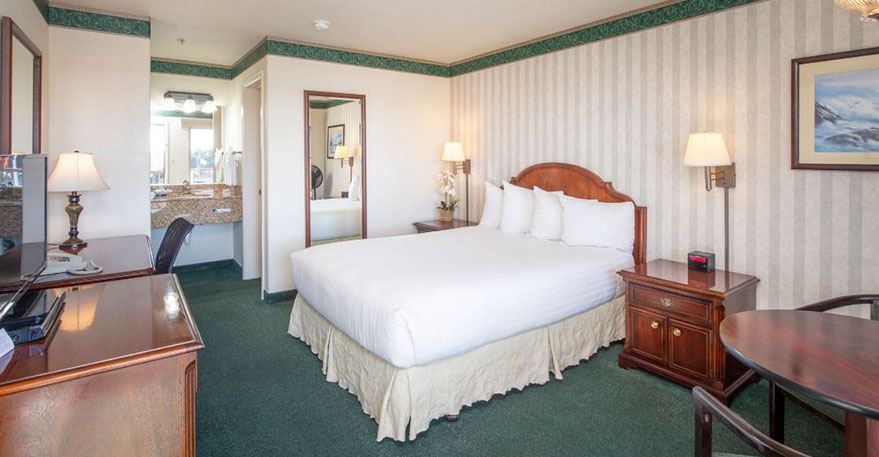 This photo shows our cozy guest room with a queen bed, 2 night stands, lamps, alarm clock and full length mirror.